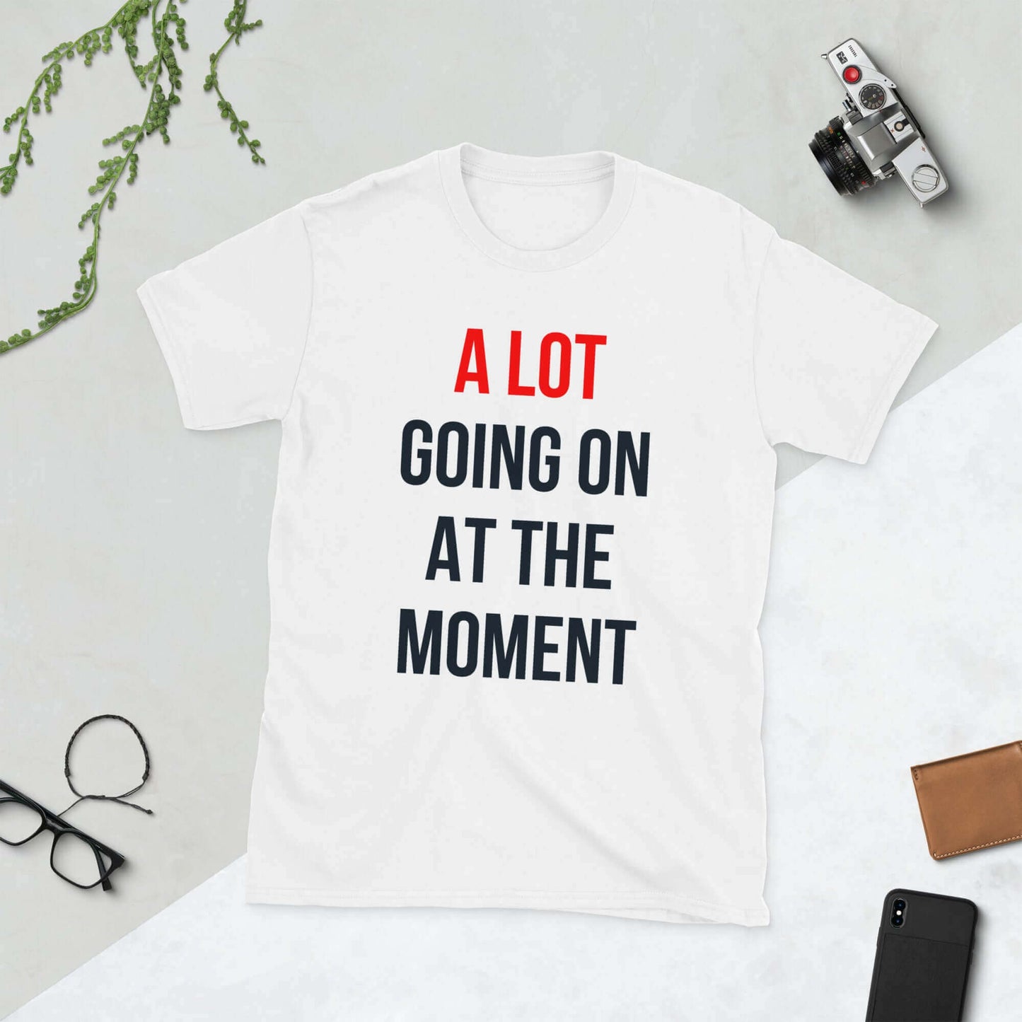 "A lot going on at the moment shirt displayed on a flat surface with accessories around it"