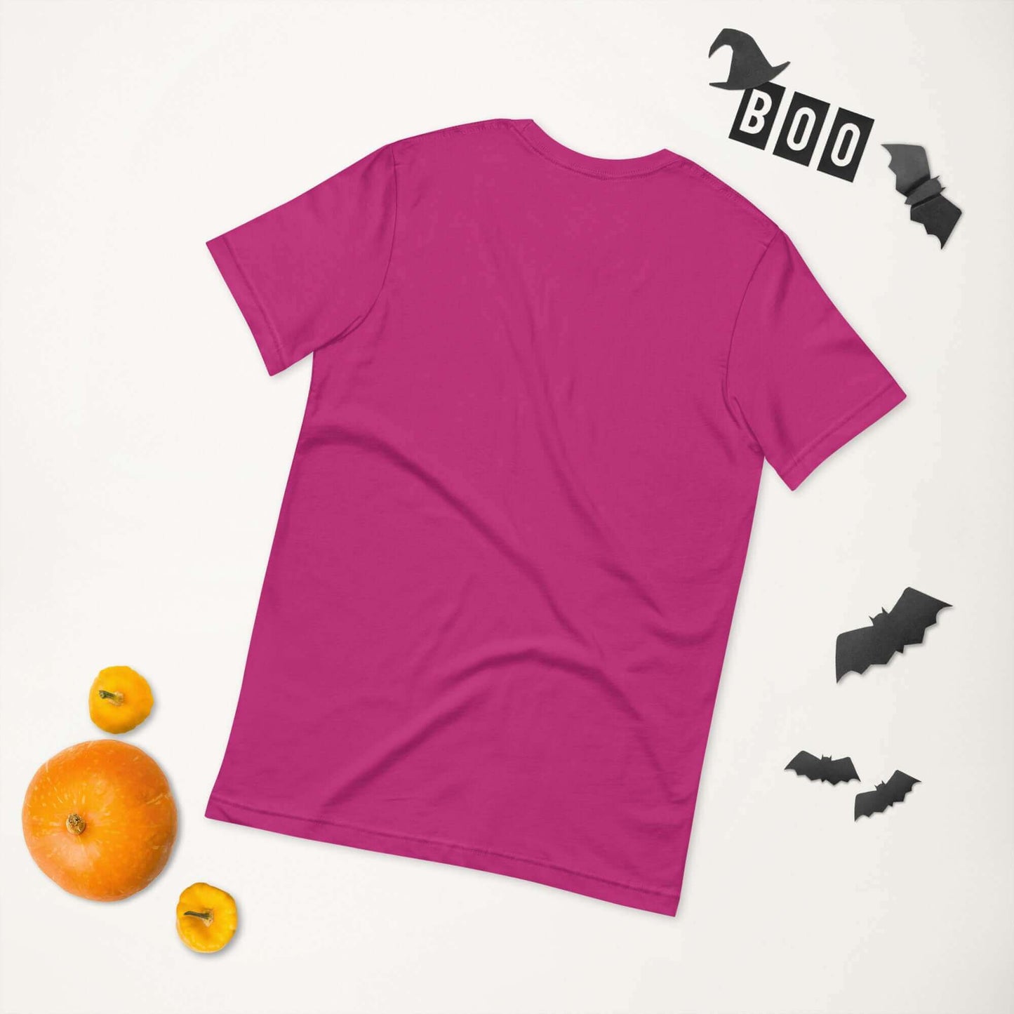 Pink unisex t-shirt shown from the back surrounded by Halloween decorations with bats and BOO letters