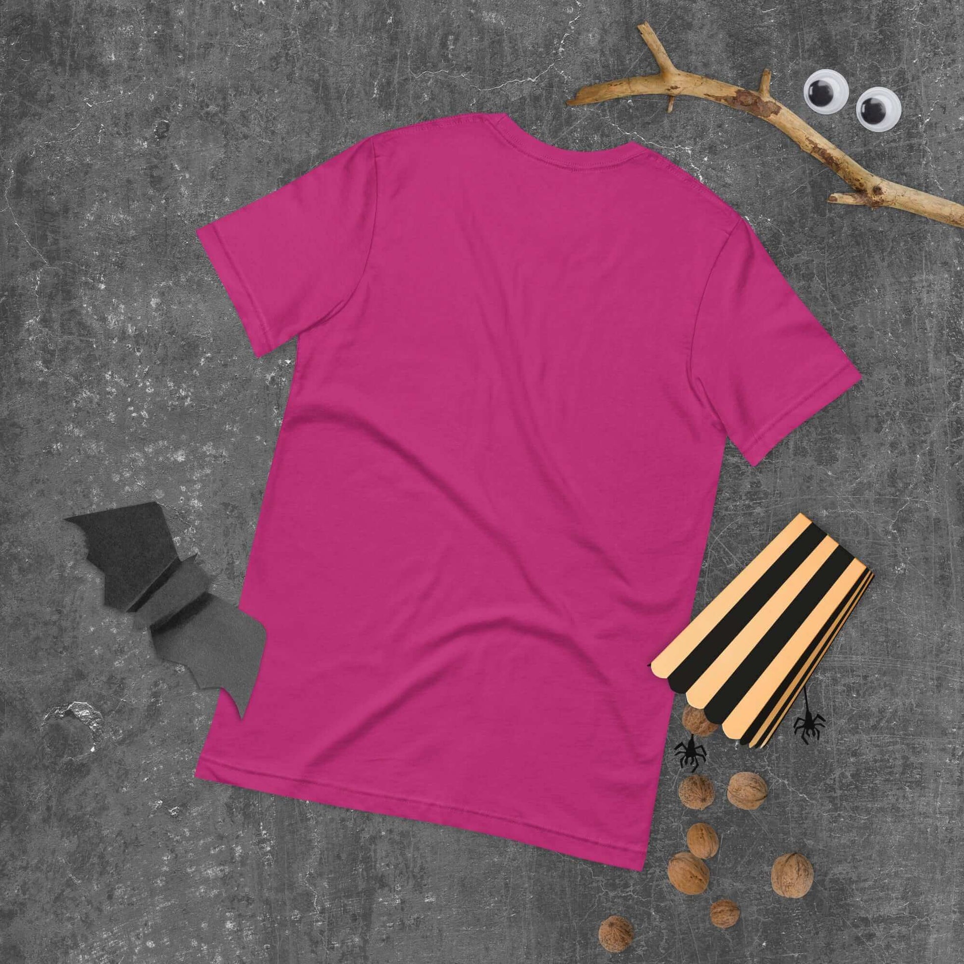 Back view of pink unisex t-shirt with Halloween-themed decorations on gray background