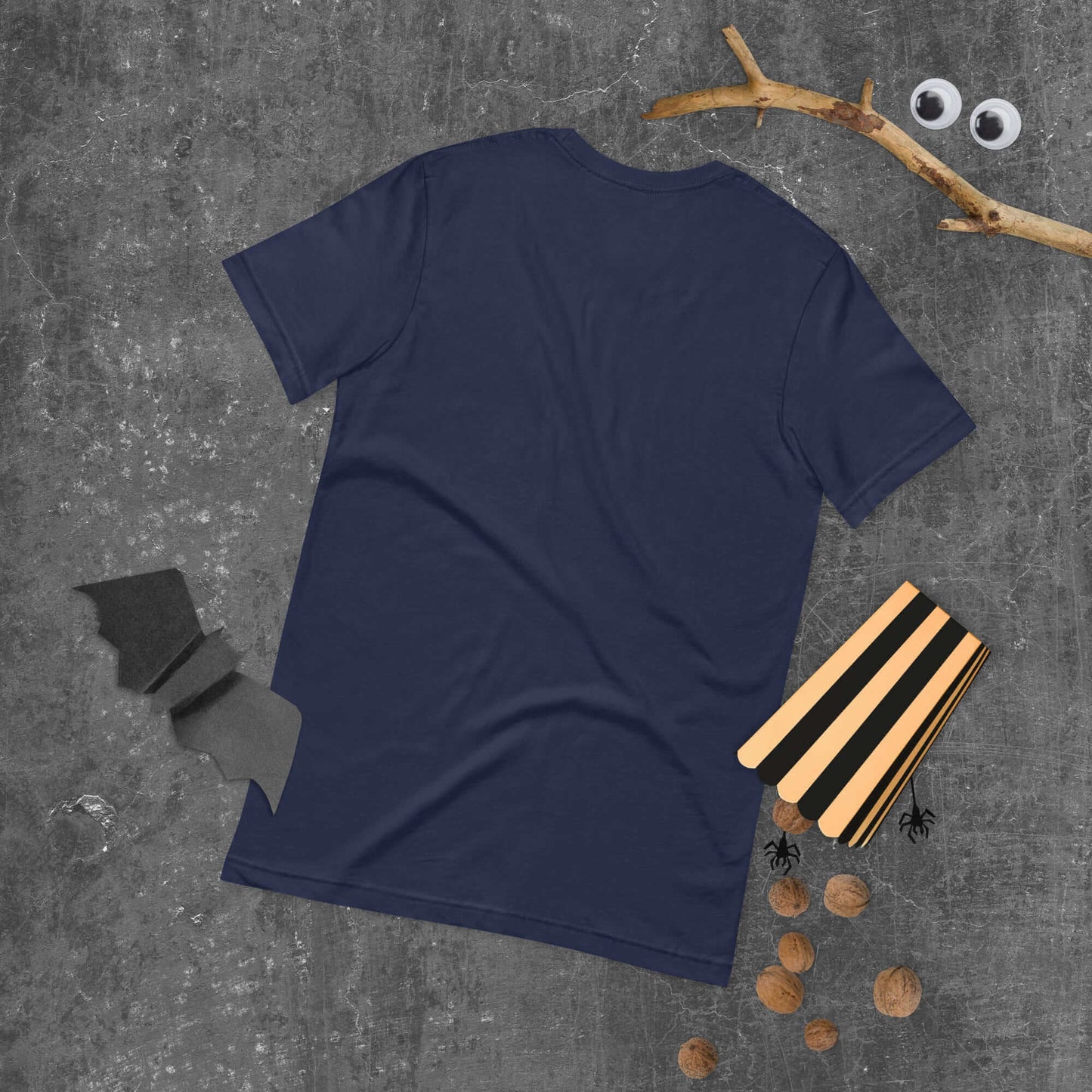 Navy unisex t-shirt displayed on concrete background with Halloween decorations.